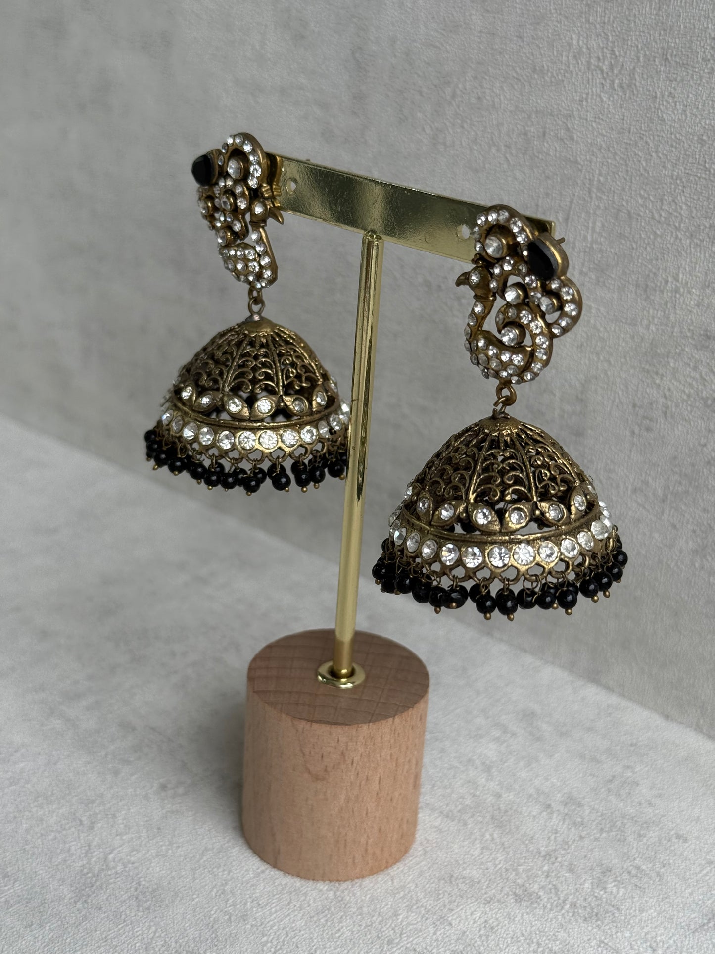 Ayura Designs Mayurika Jhumkis – Antique Gold Jhumkis with Crystal Stones, Black Beads & Peacock Motif