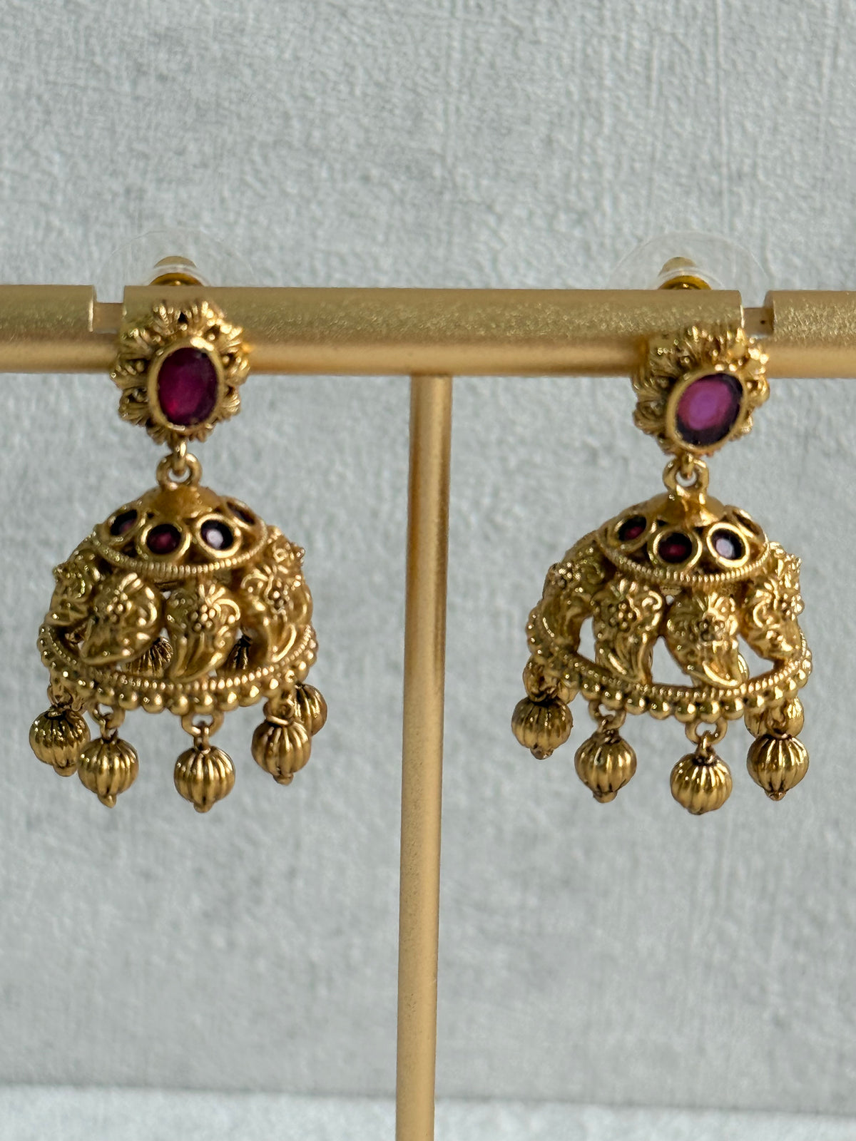 Ayura Designs Savya Jhumkis – Rani Pink Stones, Floral Motifs & Antique Gold Finish