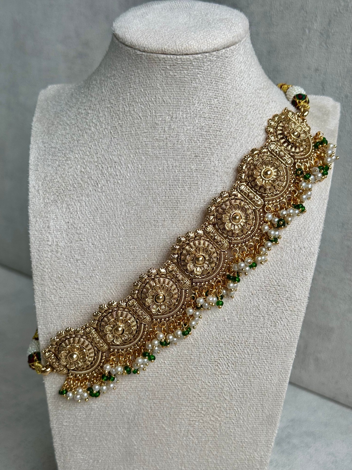 Ayura Designs Nooriya Choker Set with Jhumkis & Tikka: Exquisite Gold-Tone Ensemble Adorned with White & Green Beads