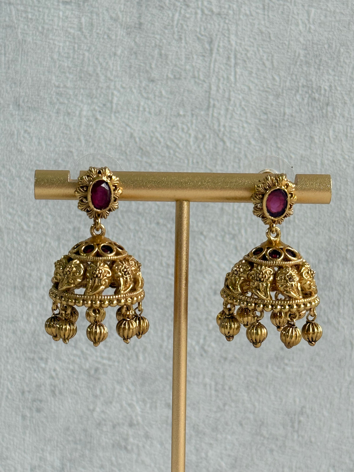 Ayura Designs Savya Jhumkis – Rani Pink Stones, Floral Motifs & Antique Gold Finish